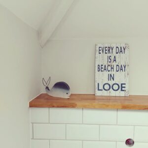 Every day is a beach day in Looe sign in an en suite toilet with a whale figurine to the side