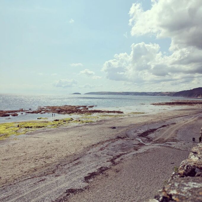 Looking down over Downderry beach towards Seaton Beach on a sunny day and the tide is out.