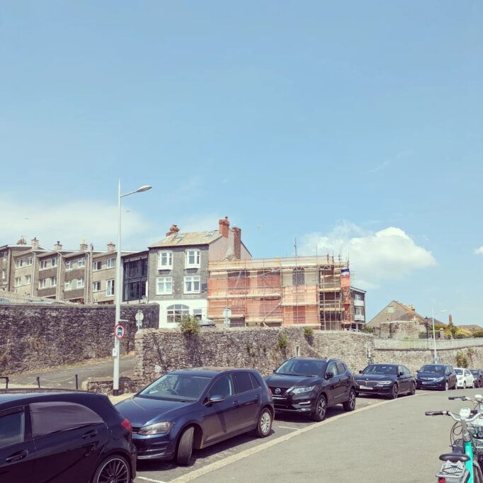 Scaffold on building near Plymouth Hoe. Car parked on the street and blue sky.