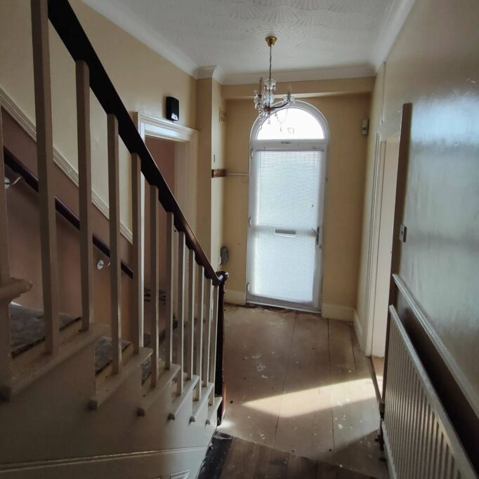 Ground floor hallway bye front door. Staircase coming down on the left. Glazed arched front door.
